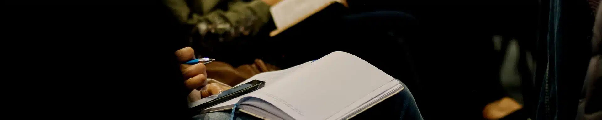 someone taking notes on paper with pen