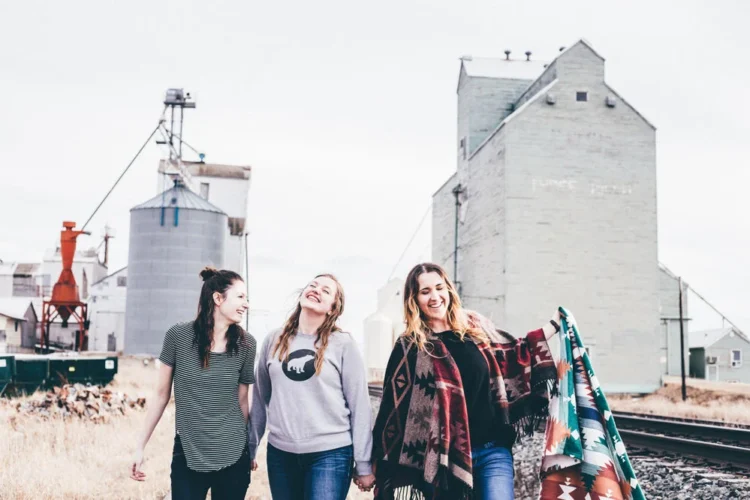 three women holding hands and smiling post